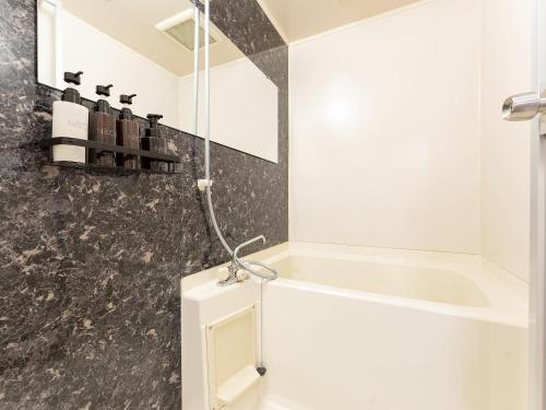 a bathroom with a bath tub and a sink at Livemax Resort Yuhigaura Kitu Onsen in Kyotango