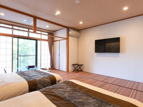 a bedroom with two beds and a flat screen tv at Livemax Resort Yuhigaura Kitu Onsen in Kyotango