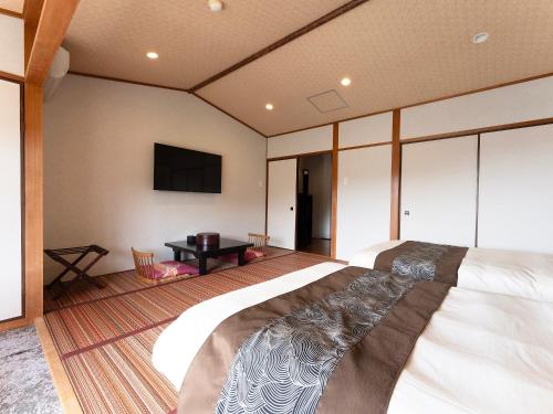 a bedroom with a large bed with a tv on the wall at Livemax Resort Yuhigaura Kitu Onsen in Kyotango