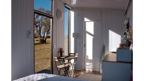 a bedroom with a window and a table and chairs at Orana Cabin by Tiny Away in Cherry Tree Pool