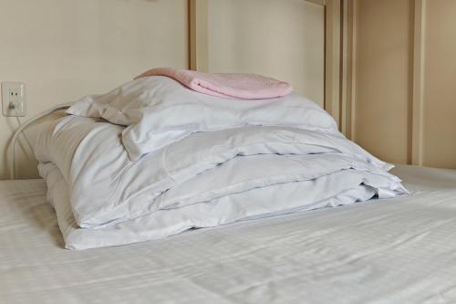 a bed with white sheets and a pink blanket at HOSTEL198 in Osaka