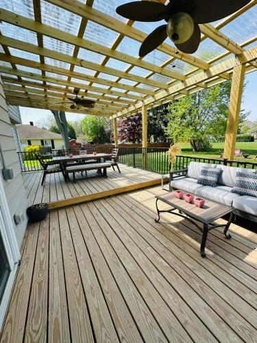 a wooden deck with a pergola with a couch and tables at The Peaceful Perch Retreat Near NYC Elle's Home in Trenton