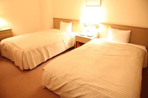 a hotel room with two beds and a table with a phone at Izumigo AMBIENT Tateshina Hotel in Tateshina