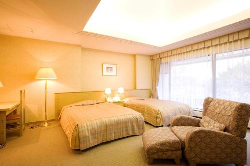 a hotel room with two beds and a chair at Izumigo AMBIENT Tateshina Hotel in Tateshina