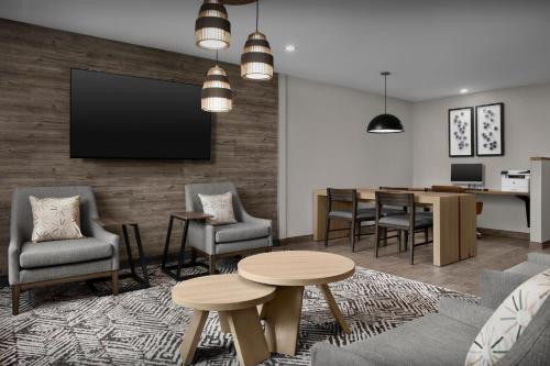 a living room with a tv and a table and chairs at Candlewood Suites Jacksonville Southpoint in Jacksonville