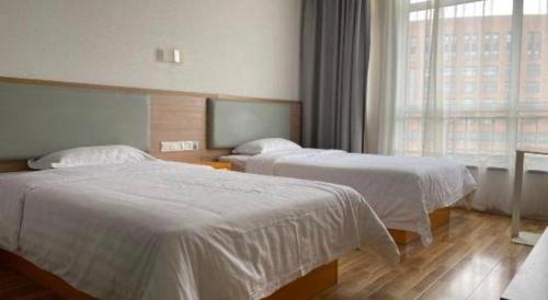 a hotel room with two beds and a window at 7Days Inn Tianjin Airport NO.1 Bridge Branch in Tianjin
