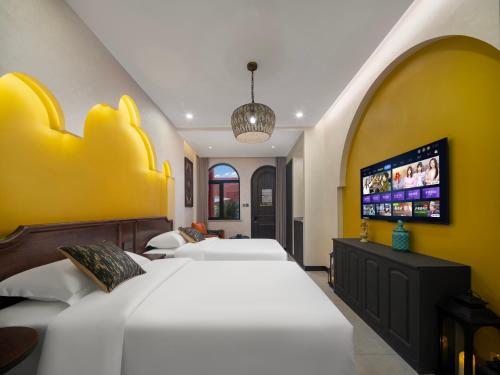 a bedroom with two beds and a flat screen tv at 浮生居设计师民宿 in Yining Airport