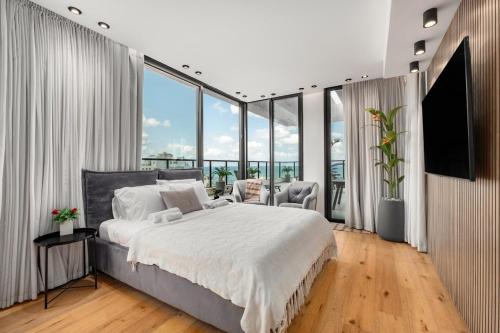 a bedroom with a large bed and large windows at Pool & Jacuzzi Seaview Penthouse by Sea N' Rent in Haifa