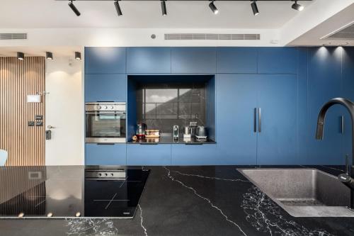a kitchen with blue cabinets and a sink at Pool & Jacuzzi Seaview Penthouse by Sea N' Rent in Haifa