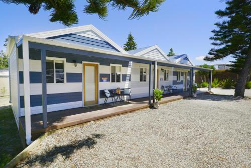 a small white and blue house with a patio at NRMA Tathra Beachfront Holiday Park in Tathra