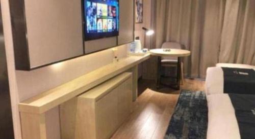 a hotel room with a television on a wall at Echarm Hotel Jingjiang Bus Passenger Station Fanggu Street in Jingjiang