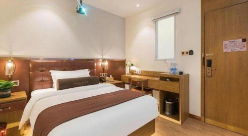 a bedroom with a large bed and a desk at James Joyce Coffetel Shijiazhuang the Mixc Jinyuan Tower Airport Bus in Shijiazhuang