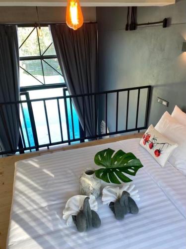 a bedroom with a bed with towels and a plant at Adoor hotel Khao Yai in Ban Rai