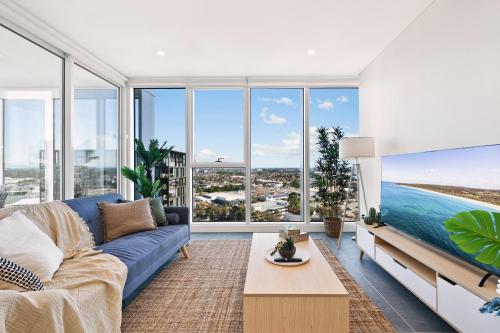 a living room with a blue couch and large windows at Breathtaking Views Modern 2BR Pool, Parking, Gym in Sydney
