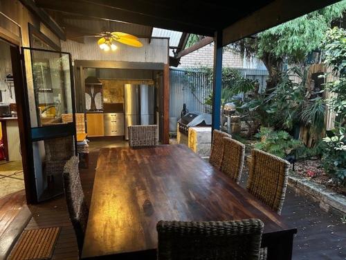 a large wooden table with chairs and a kitchen at South Terrace House - walk to everything ! in South Fremantle
