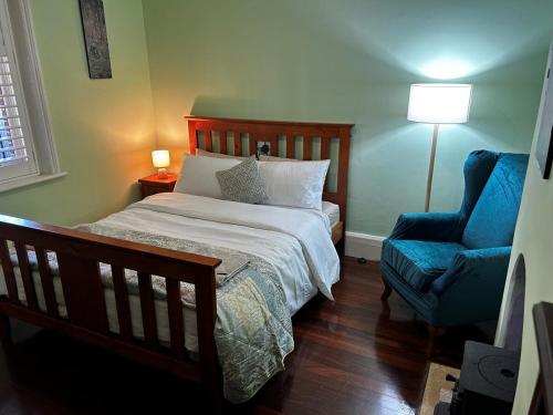 a bedroom with a bed and a blue chair at South Terrace House - walk to everything ! in South Fremantle