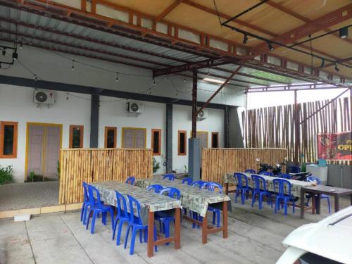 a group of tables and blue chairs in a building at AL KISWAH Homestay in Ongge