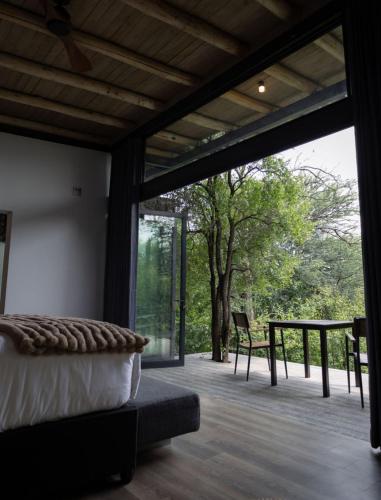 a bedroom with a large window and a table at Umoya Safari Lodge in Matlhagame