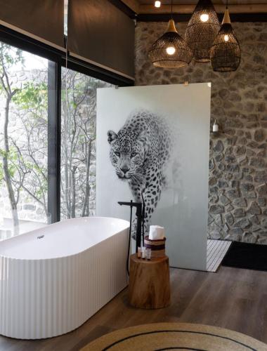 a bathroom with a bath tub and a picture of a leopard at Umoya Safari Lodge in Matlhagame