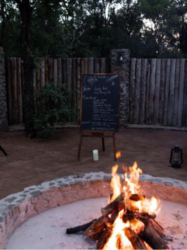 a fire pit with a sign in a yard at Umoya Safari Lodge in Matlhagame