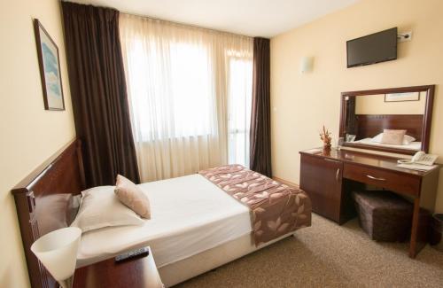 a hotel room with a bed and a desk and a mirror at Hotel Divesta - self check in in Varna City