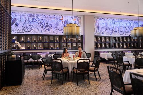 two people sitting at a table in a restaurant at Padma Hotel Semarang in Semarang