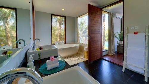 a bathroom with a bath tub and a sink at Malimbu Cliff Villa by Elite Havens in Senggigi