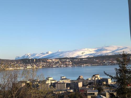 a city on the water with snow covered mountains at Sauna Apartment in Tromsø