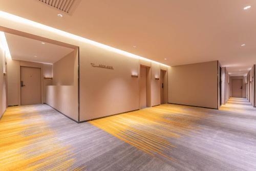 an empty room with a hallway with doors and wooden floors at 沃德德州汽车总站万达广场店 in Dezhou
