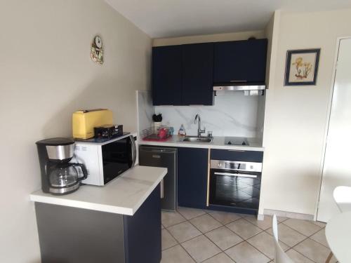 une petite cuisine avec des placards noirs et un four micro-ondes dans l'établissement Charmant appartement 2 pièces avec loggia et parking à deux pas de la plage - FR-1-712-93, à Villers-sur-Mer