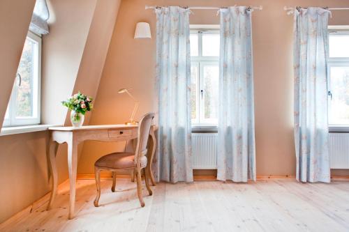 a home office with a desk and windows at Gut Sarnow - Hotel und Restaurant in Schorfheide