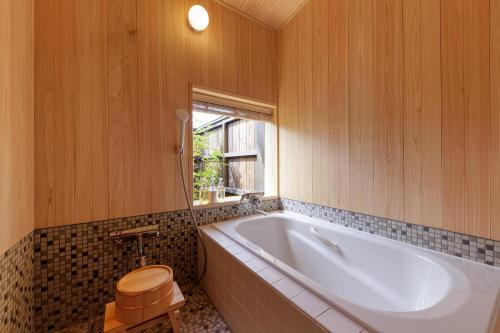 伊势市Nipponia Hotel 伊勢河崎 商人町的带浴缸、马桶和窗户的浴室