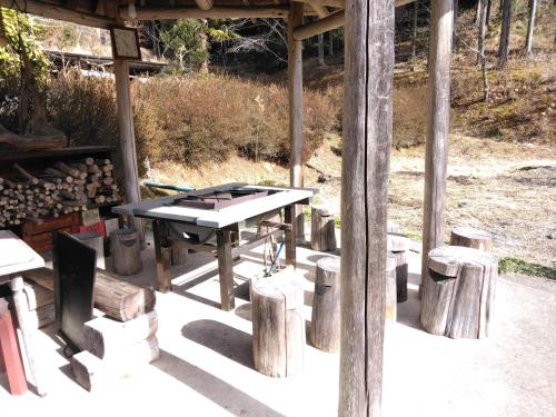 a picnic table in a pavilion with logs around it at BANRYU 萬龍 バンリュウ in Iida