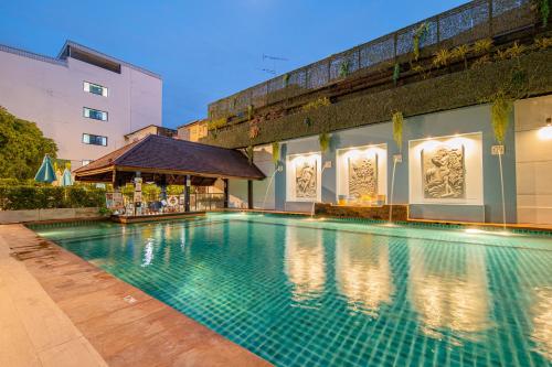 a swimming pool in front of a building at Sunbeam Hotel Pattaya in Pattaya