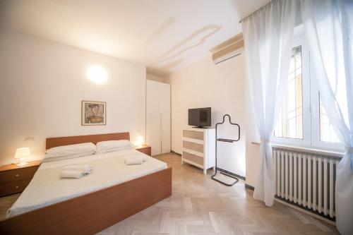 een witte slaapkamer met een bed en een televisie bij Hotel Colombo in Riccione