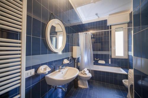 W wyłożonej niebieskimi kafelkami łazience znajduje się umywalka i toaleta. w obiekcie Hotel Colombo w mieście Riccione