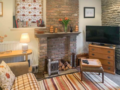 un salon avec une cheminée et une télévision dans l'établissement Appleshine Cottage, à Almondbury