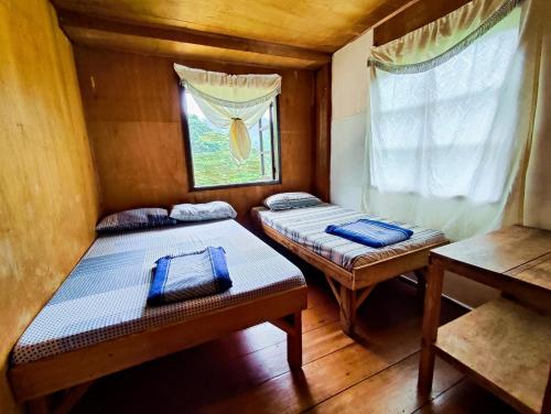 two beds in a small room with a window at BATAD Simons Viewpoint Inn and Pizza Restaurant in Banaue