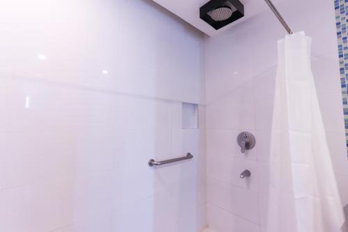 a white bathroom with a shower with a curtain at Hotel Dreamworld North Edsa in Manila