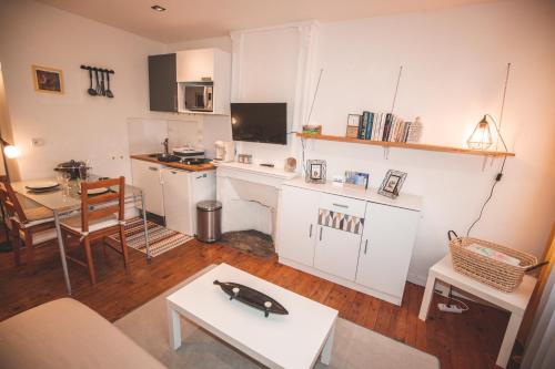 Il comprend un salon doté d'une cuisine blanche avec une table. dans l'établissement Cocooning studio Rue Raphaël, au Puy-en-Velay