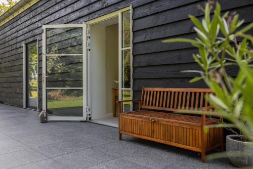 a wooden bench sitting outside of a house with a door at B&B Iets Zeeuws in Kats
