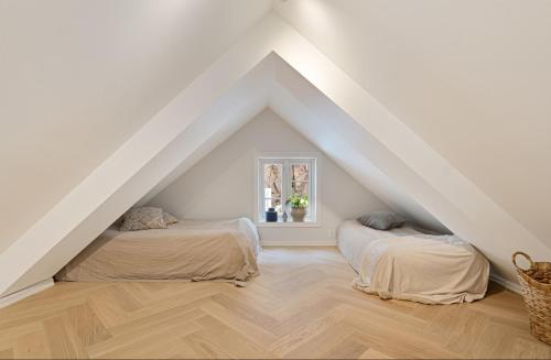 two beds in a attic room with white walls and wooden floors at Idylliske Nordbyen - Brygga i Tønsberg in Tønsberg