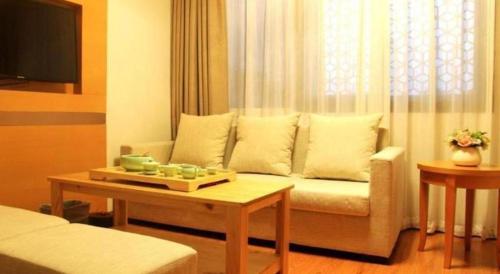 a living room with a couch and a table at GreenTree Inn Fuzhou Gulou District West Xierhuan Road Zuohai Park in Fuzhou