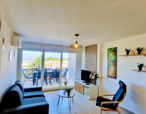 un salon avec un canapé et une télévision dans l'établissement THAU-INDIGO, Appt Neuf, Standing, Prox Plages, Terrasse, Parking, Climatisé, à Sète