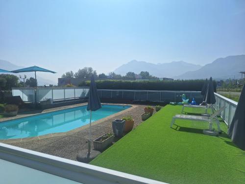 Un balcón con piscina con césped y sombrillas. en Hotel le Foron, en La Roche-sur-Foron