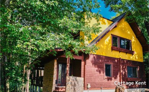 a yellow and red house surrounded by trees at Lodge Kent & Cottage Kent in Hokuto