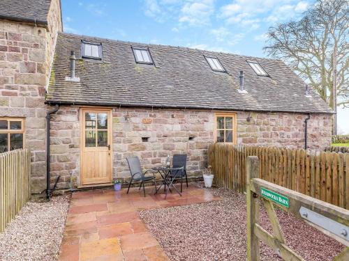 a stone house with two chairs and a fence at Herdwick Barn - Uk46732 in Wootton