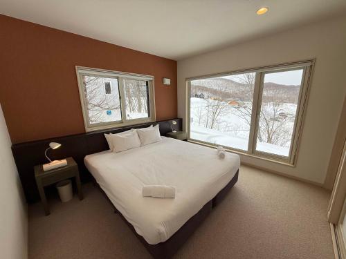 a bedroom with a large bed and a large window at Yutaka 1 in Kutchan