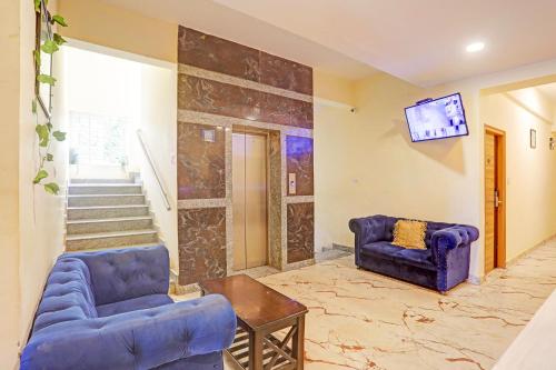a living room with two blue chairs and a tv at FabExpress Kings Palace Manyata in Bengaluru
