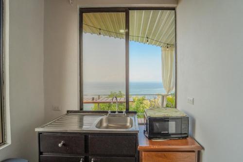 a kitchen with a sink and a microwave and a window at An apartment with an ocean view in Playa Islita in Islita